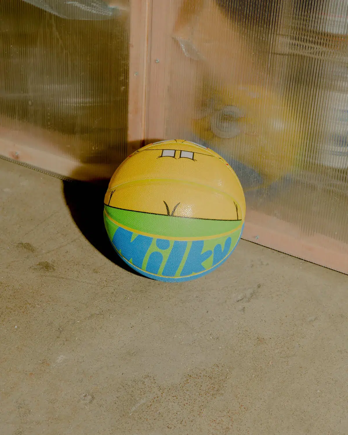 A yellow and blue LV Camo Basketball Ball laying on the ground.