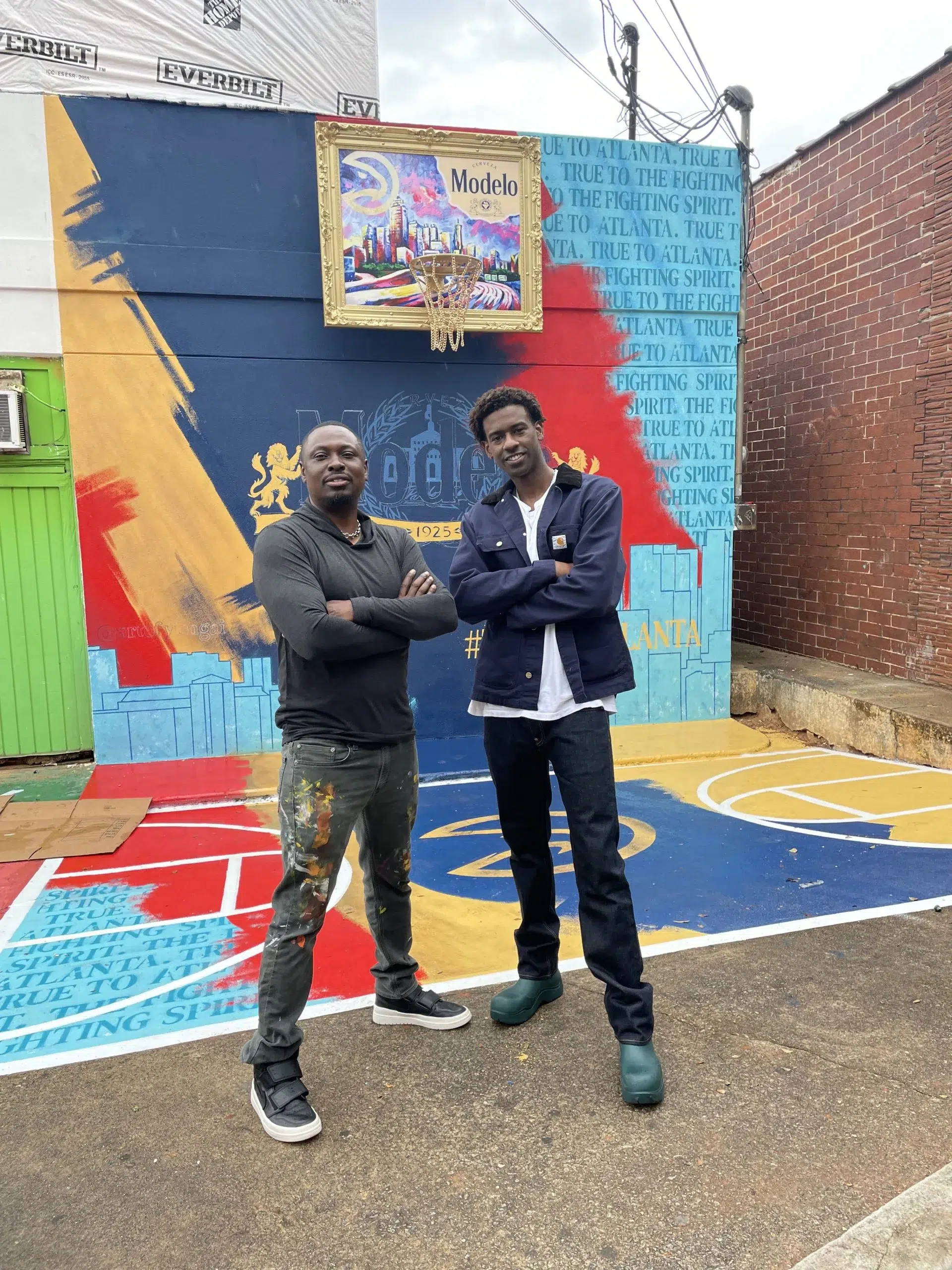 Two men standing in front of a painted basketball court.