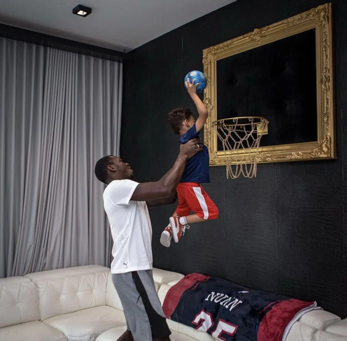 A man and a child playing basketball in a living room.