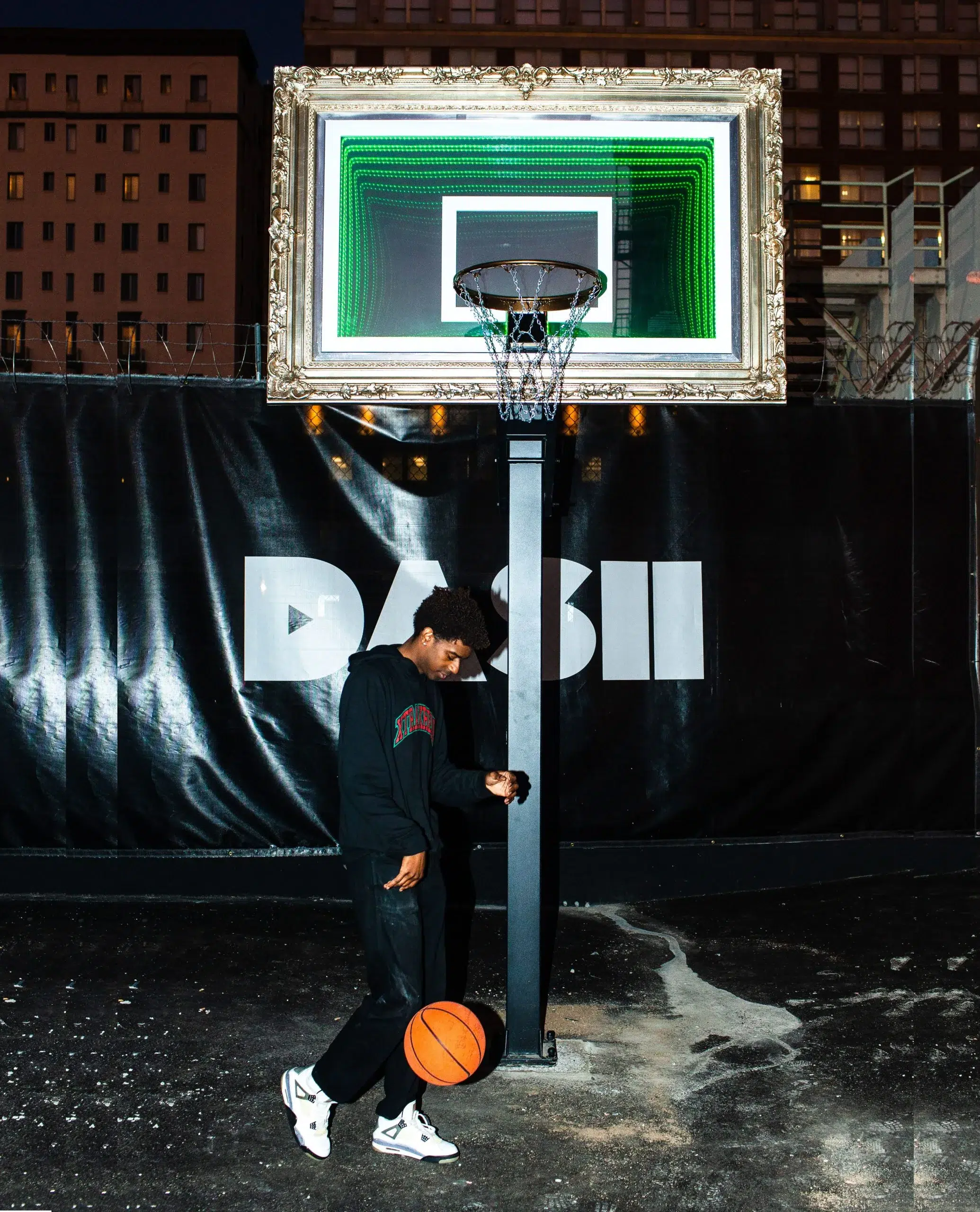 A man holding a basketball in front of a basketball hoop.