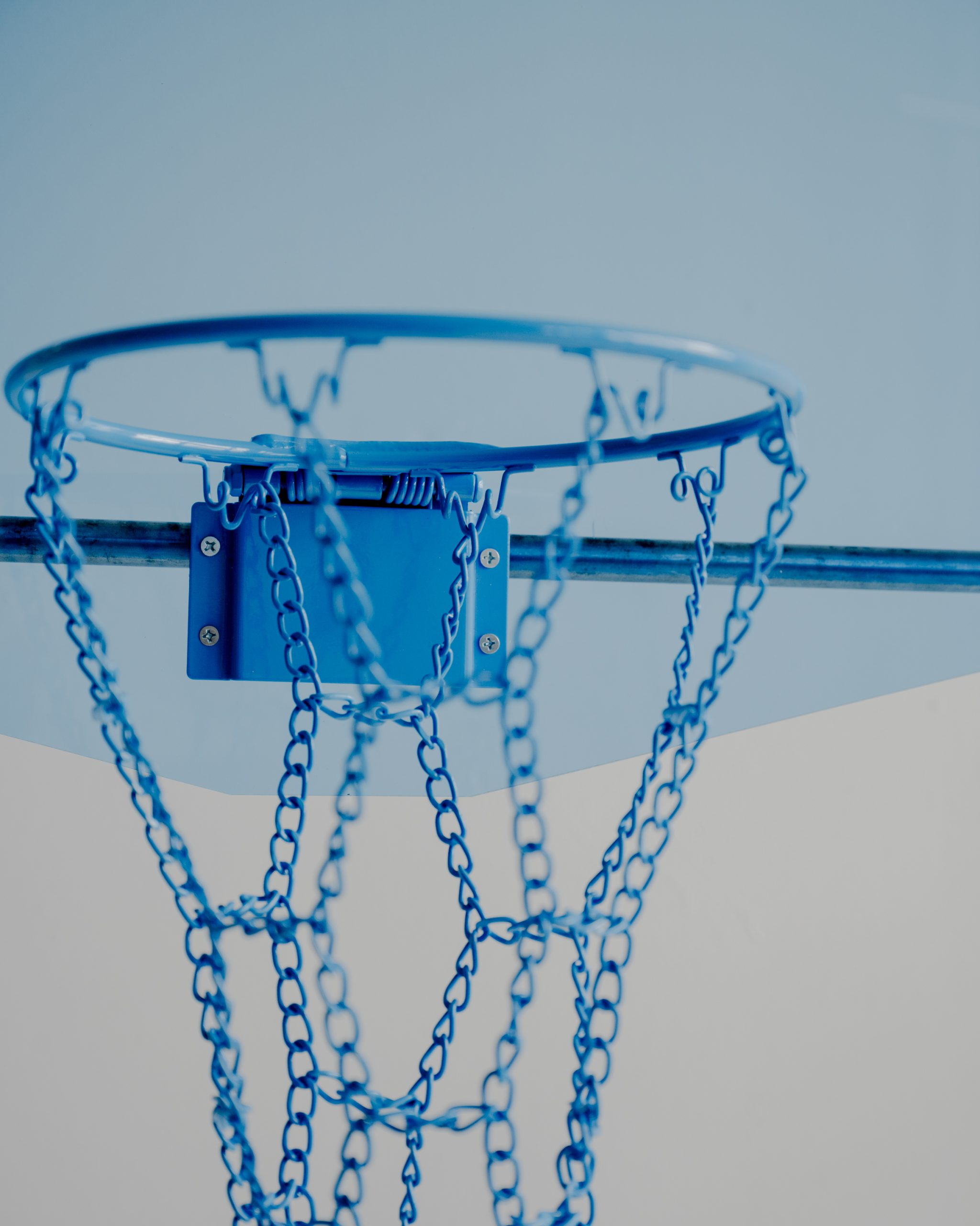 A vibrant blue Acrylic Hoop - Blue with a sturdy chain net stands out against the clear blue sky, epitomizing the thrill of outdoor play.